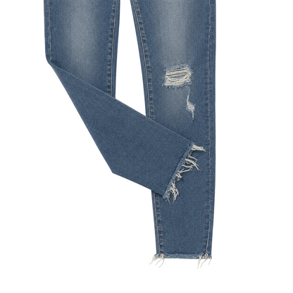 Close-up of blue denim jeans with a ripped knee detail, frayed raw hems, and a folded leg on a white background.